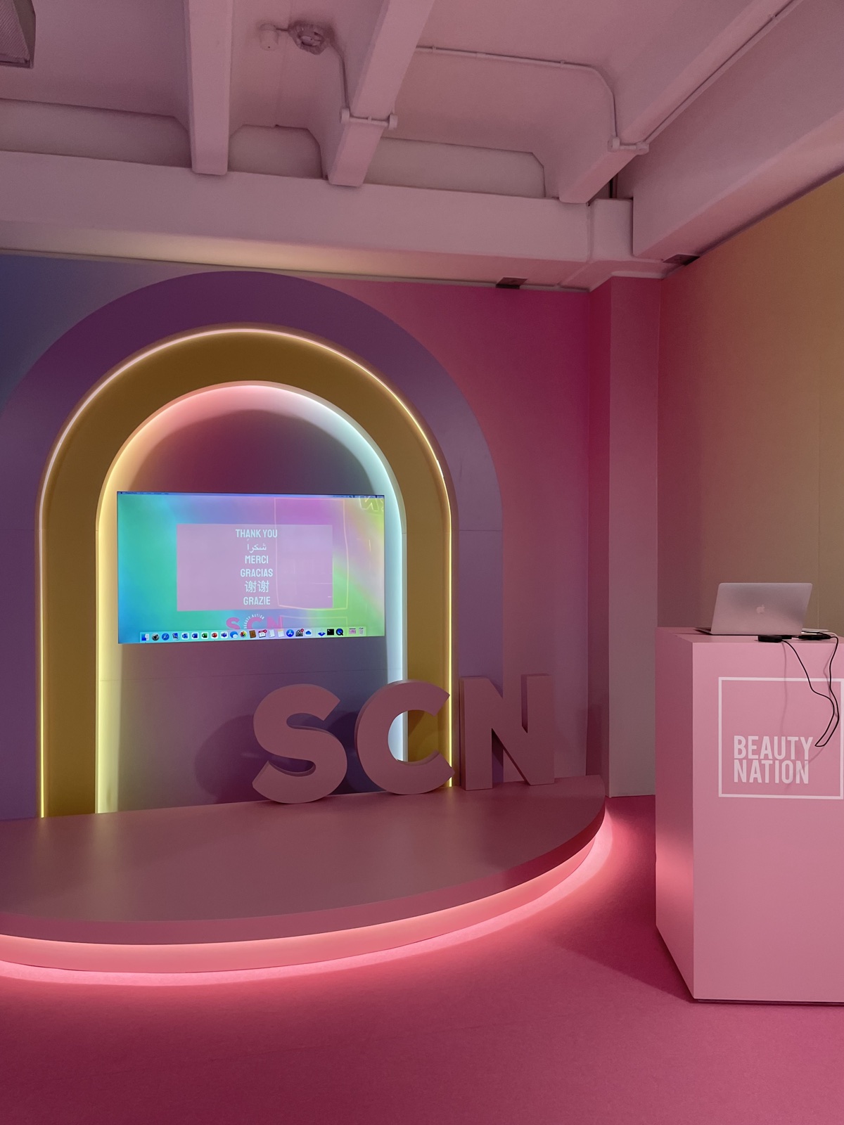 The Skin Care Network pop-up stage — neon-lit arch with SCN letters and a Beauty Nation plinth